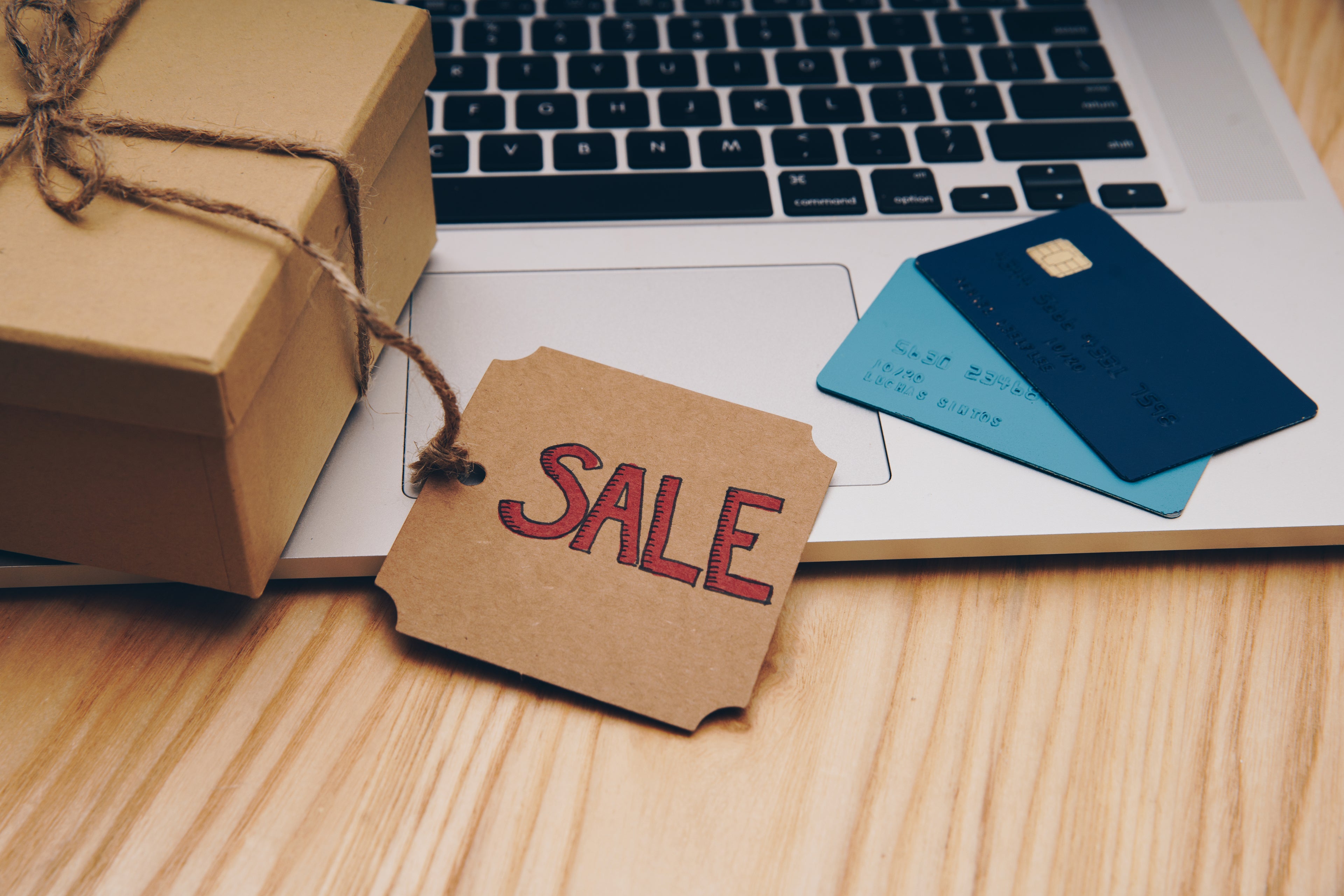 Ein Laptop mit einem Paket und einem SALE-Schild.